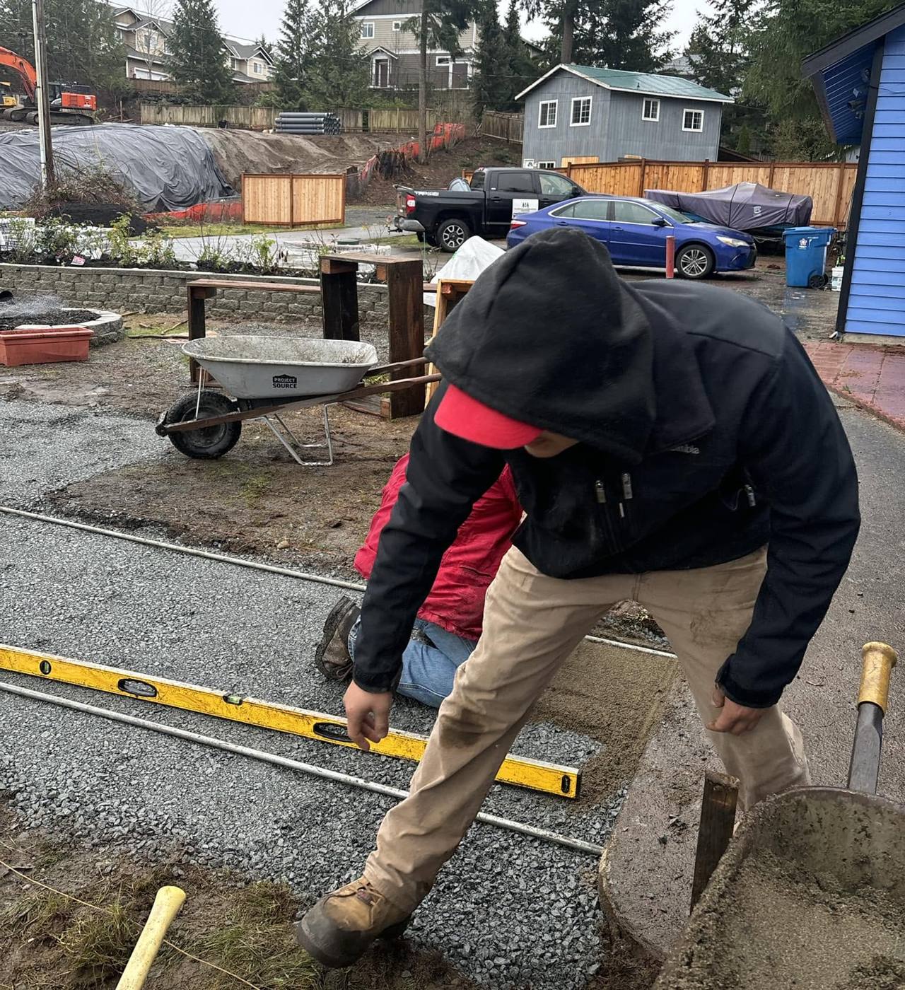 Crew member screeding the gravel base for a paver patio with a level and rail